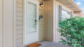 A house entrance with a white door, a welcome sign, and a mailbox.