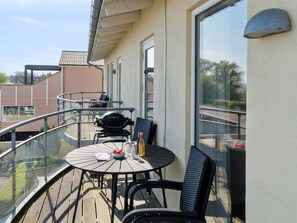 Ein Balkon mit rundem Tisch und Stühlen, einem Grill und Blick auf die Umgebung.