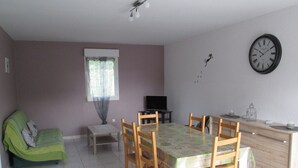 A dining area with a table and chairs, a sofa, a television, and a clock on the wall. - Gite in the heart of the Périgord Noir (Tamniès)