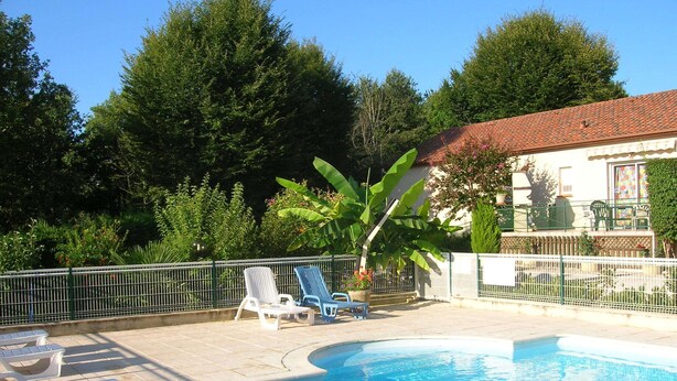 A swimming pool with lounge chairs and a fenced patio area. - Gite in the heart of the Périgord Noir (Tamniès)