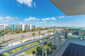 Ein Balkon mit Blick auf eine Straße, Palmen und Gebäude im Hintergrund.