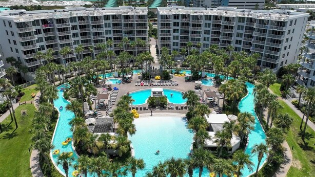 Un hôtel doté d’une piscine centrale, entourée de palmiers et offrant plusieurs espaces de baignade.