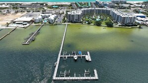 Vue aérienne d’une marina avec des bateaux amarrés, une jetée et des bâtiments environnants.