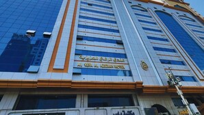 Un hôtel moderne, avec une façade en verre remarquable et une enseigne indiquant qu’il s’agit de l’hôtel Al Refa Al Azziar.