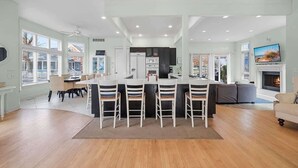 A spacious kitchen with a central island, a dining area with chairs, a sofa, and a TV. - Golf Cart, Resort Pools, Sandy Beach, Pickleball (Michigan City)