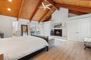 A bedroom with a large bed, a fireplace, and a view of the outdoors. - Juniper Presents: Golf Cart, Resort Pools, Sandy Beach, Pickleball (Michigan City)