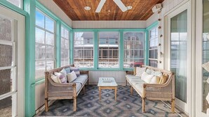 A sunroom with two wicker sofas, a small table, and a ceiling fan. - Golf Cart, Resort Pools, Sandy Beach, Pickleball (Michigan City)