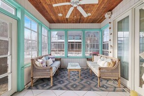 A sunroom with two wicker sofas, a small table, and a ceiling fan. - Golf Cart, Resort Pools, Sandy Beach, Pickleball (Michigan City)