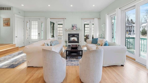 A spacious living room with a fireplace, two sofas, a coffee table, and large windows. - Golf Cart, Resort Pools, Sandy Beach, Pickleball (Michigan City)