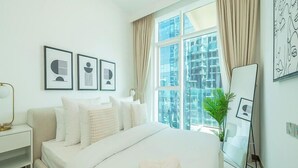 Ein modernes Hotelzimmer mit einem großen Bett, einem Nachttisch, einem Spiegel und gerahmten Kunstwerken an der Wand.