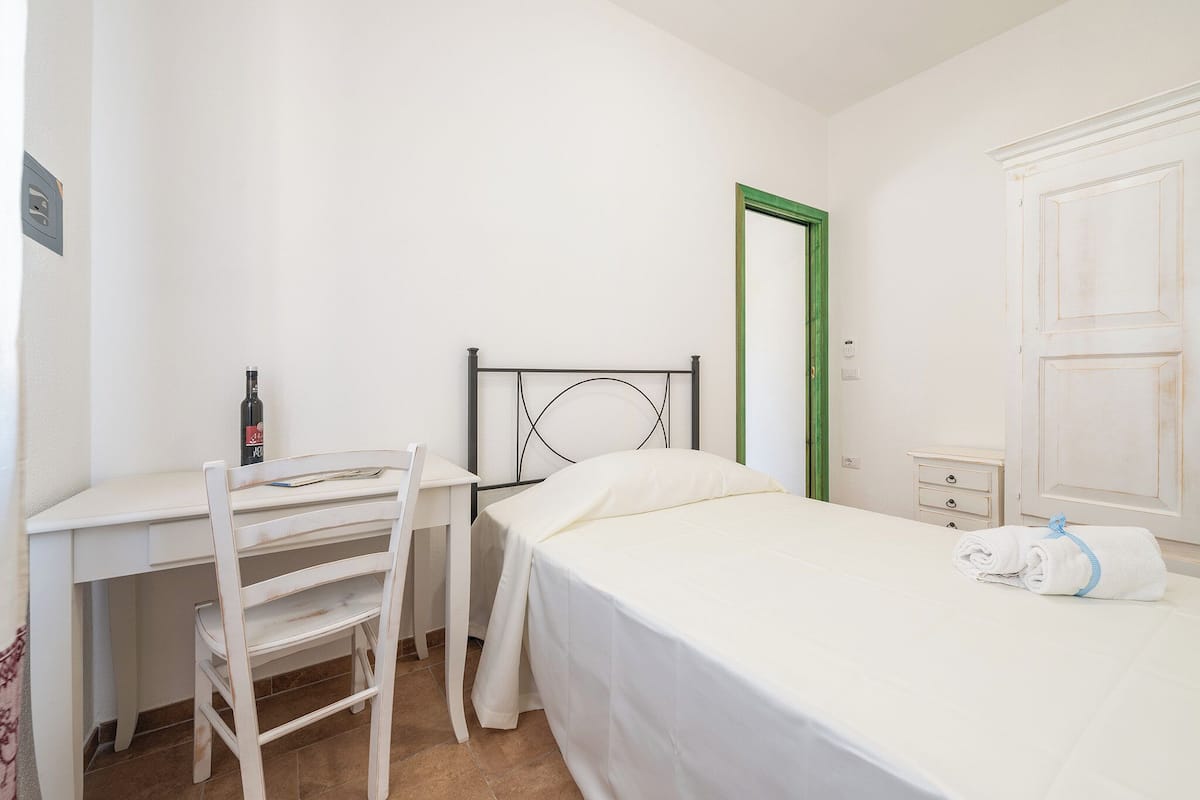 Une chambre à coucher avec un lit, un bureau, une chaise et une armoire.