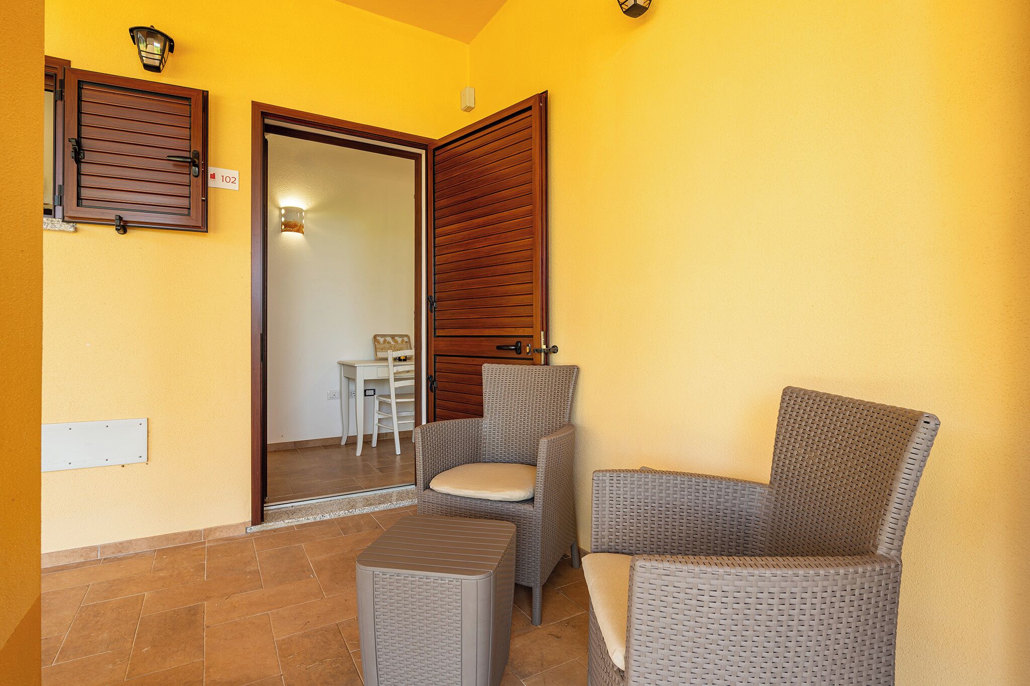 A room with a sliding door, wicker furniture, and a small table.