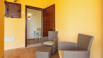 A room with a sliding door, wicker furniture, and a small table.