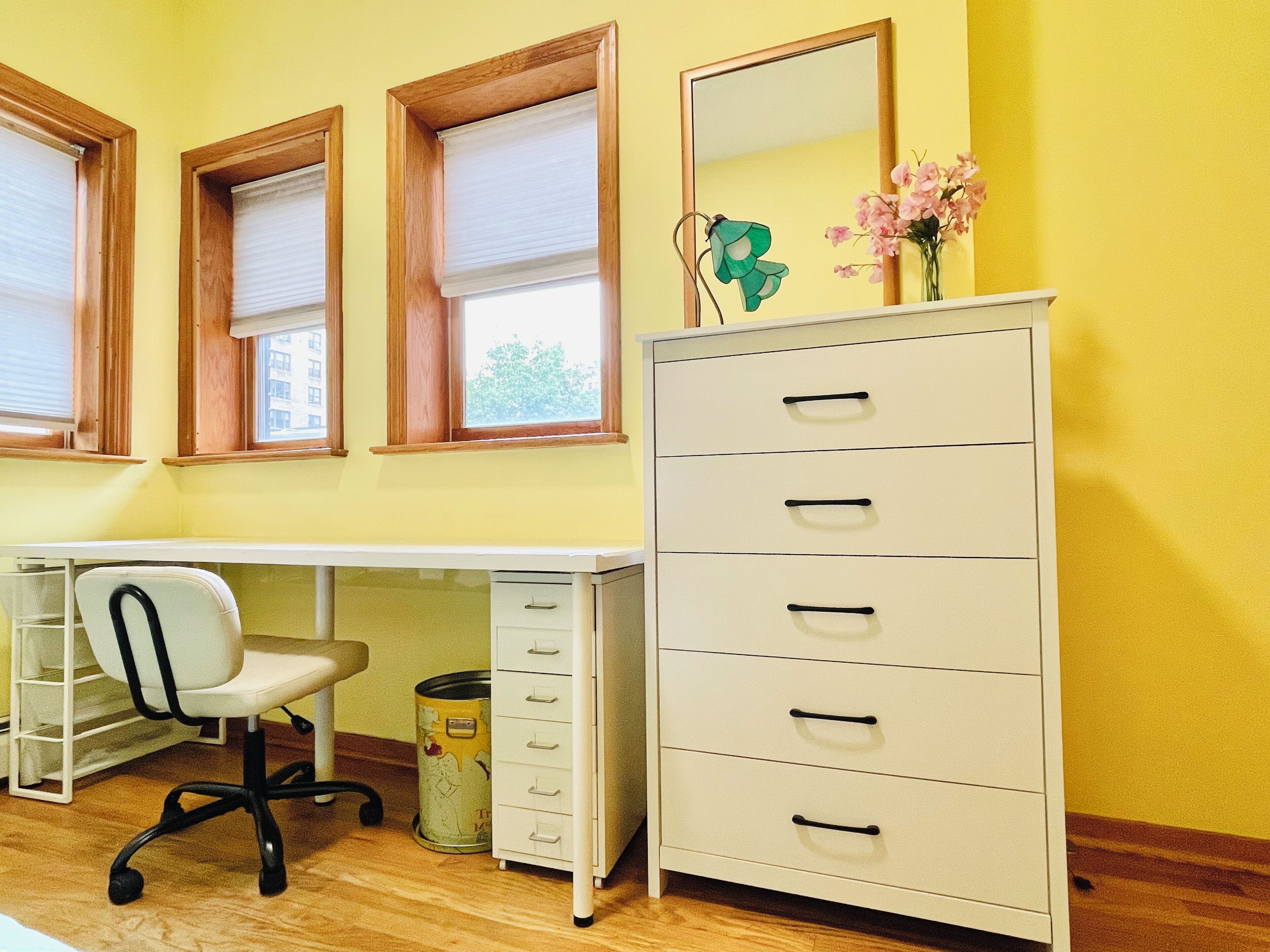 A room with a desk, chair, and a tall filing cabinet.