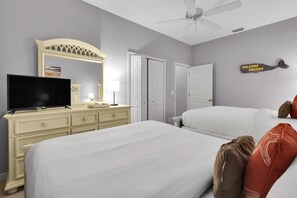 Hotelkamer met een bed, een televisie, een dressoir, een plafondventilator en een 'Welcome Aboard' bord.