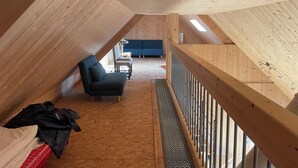 A wooden interior with a sloped ceiling, a sofa, a chair, and a small table.