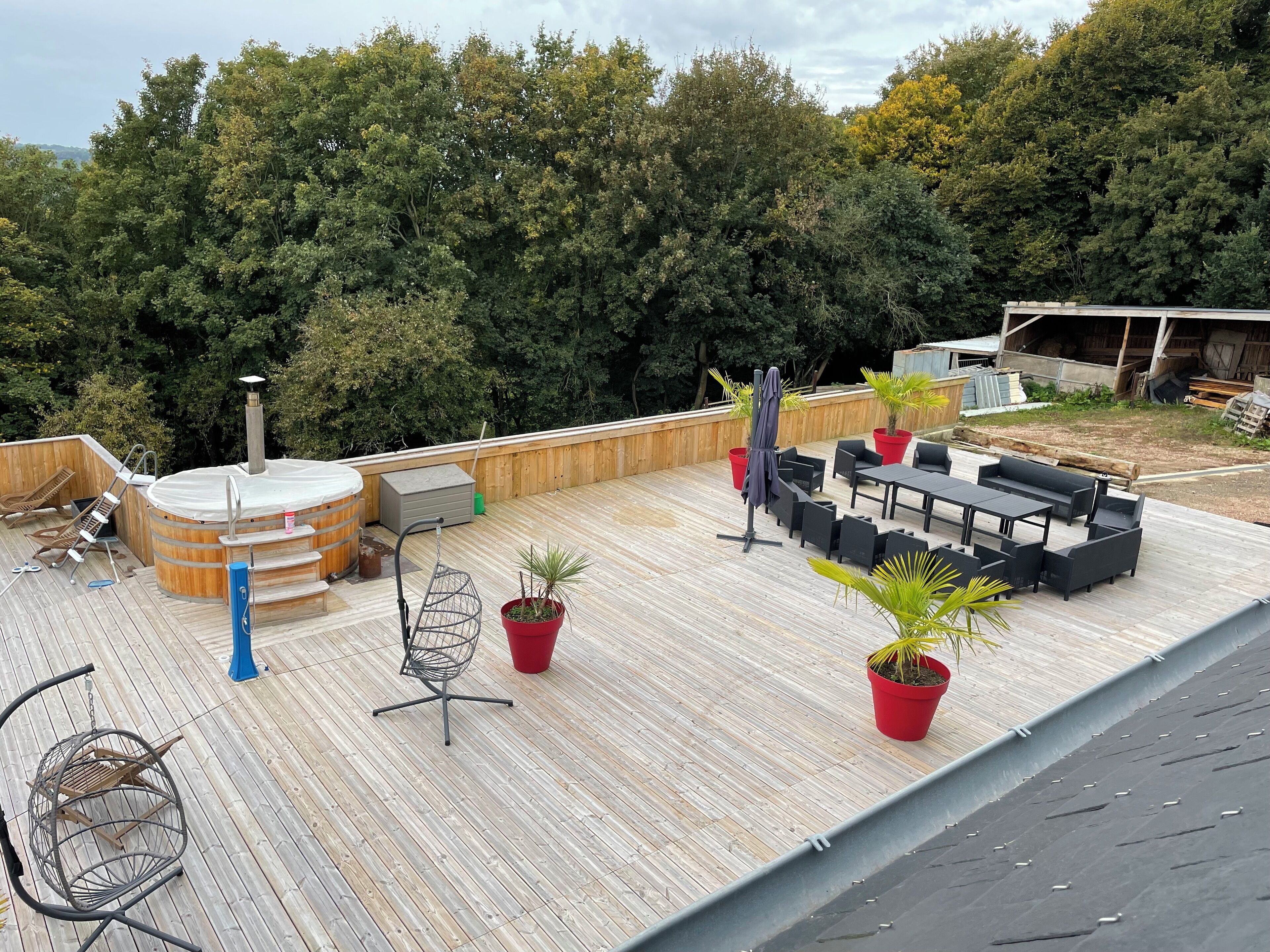 Een houten terras met buitenmeubilair, een bubbelbad en potplanten.