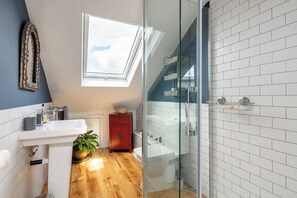 A modern bathroom with a skylight, a red cabinet, a sink, and a glass shower enclosure. - Spacious house & large garden in Leytonstone, perfect for families & groups (London)