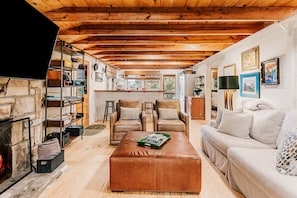 Een gezellige woonkamer met een open haard, leren fauteuils, een bank en een bijzettafeltje.