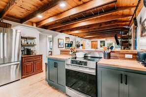 A kitchen with wooden beams, a stainless steel refrigerator, a built-in oven, and a wooden countertop. - New Listing! Mountain Views - Fire pit - Walk to downtown Cashiers (Cashiers)
