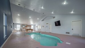Una amplia piscina interior con techo inclinado e iluminación empotrada.