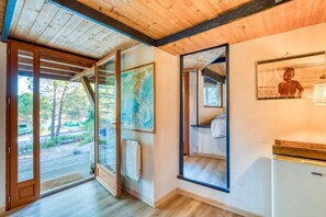 Een kamer met een houten plafond, een groot raam, een kaart aan de muur, een bed en een koelkast.
