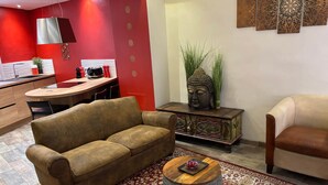A living room with a brown sofa, a wooden coffee table, a patterned rug, a Buddha statue, and a red wall.