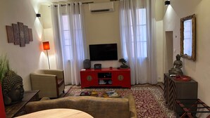 A living room with a sofa, a coffee table, a red entertainment unit, a television, and a Buddha statue.