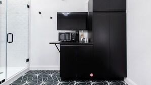 Angolo cottura compatto con frigorifero nero, forno a microonde e un piccolo piano di lavoro.