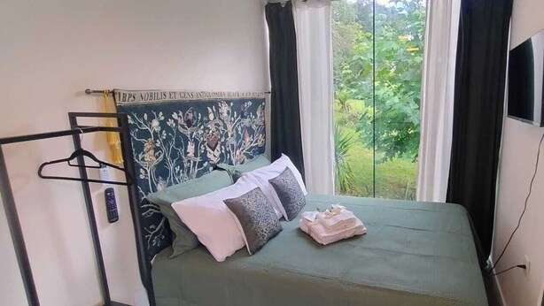 A bedroom with a bed, a TV mounted on the wall, and a window with curtains. - Medieval Village, your castle in Canela - Loft Lenister (Canela)