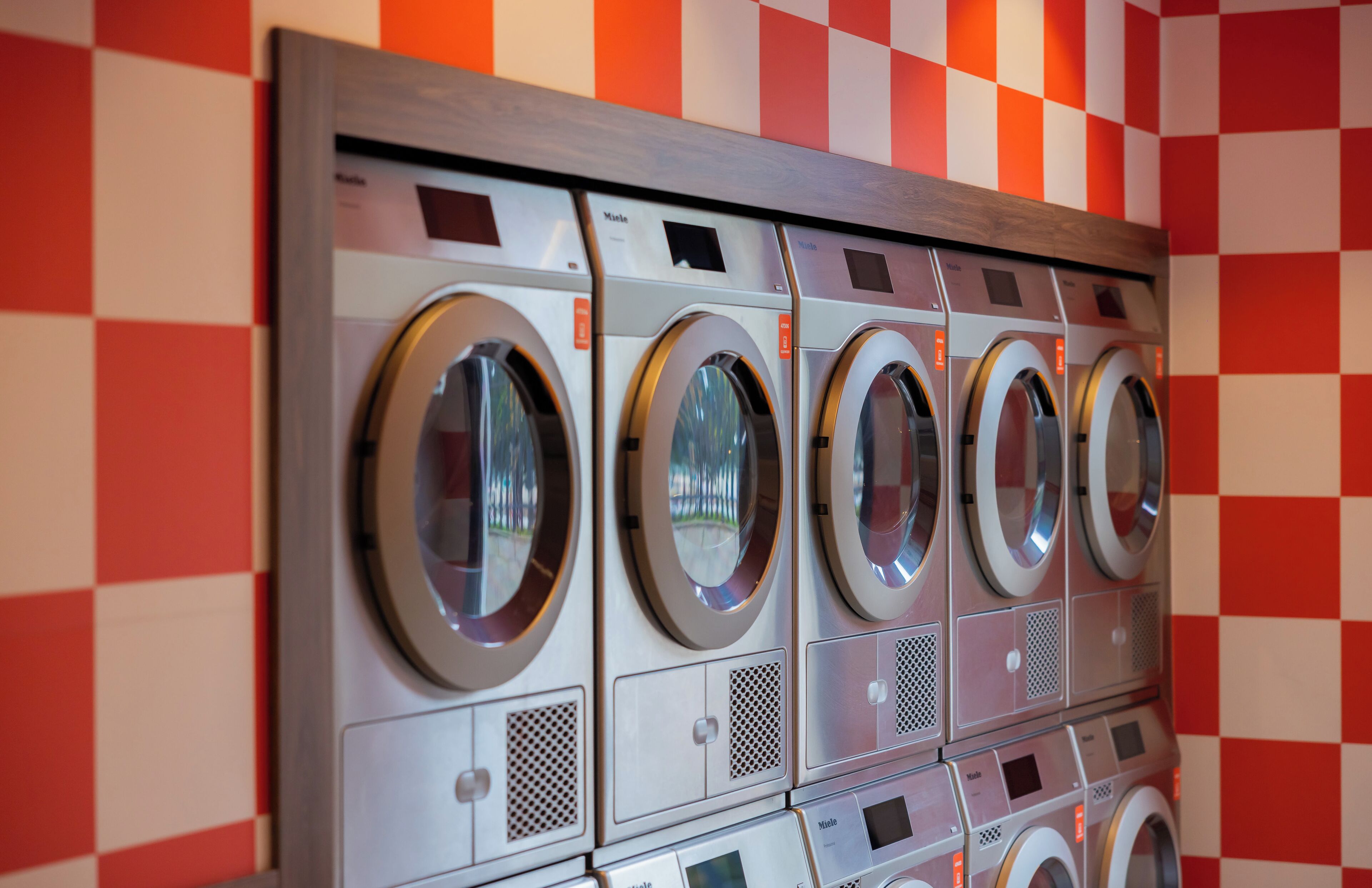 A row of front-loading washing machines in a commercial setting.