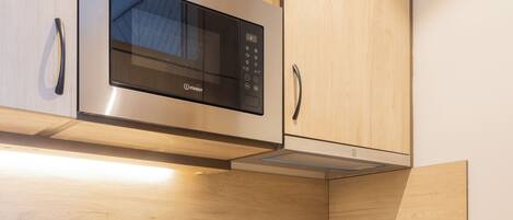 A modern kitchen with stainless steel appliances, granite countertops, wooden cabinets, and a built-in oven.