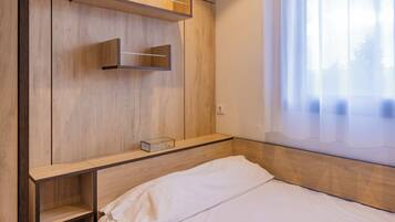 A bedroom with a wooden headboard, a bed with white bedding, and built-in shelves.