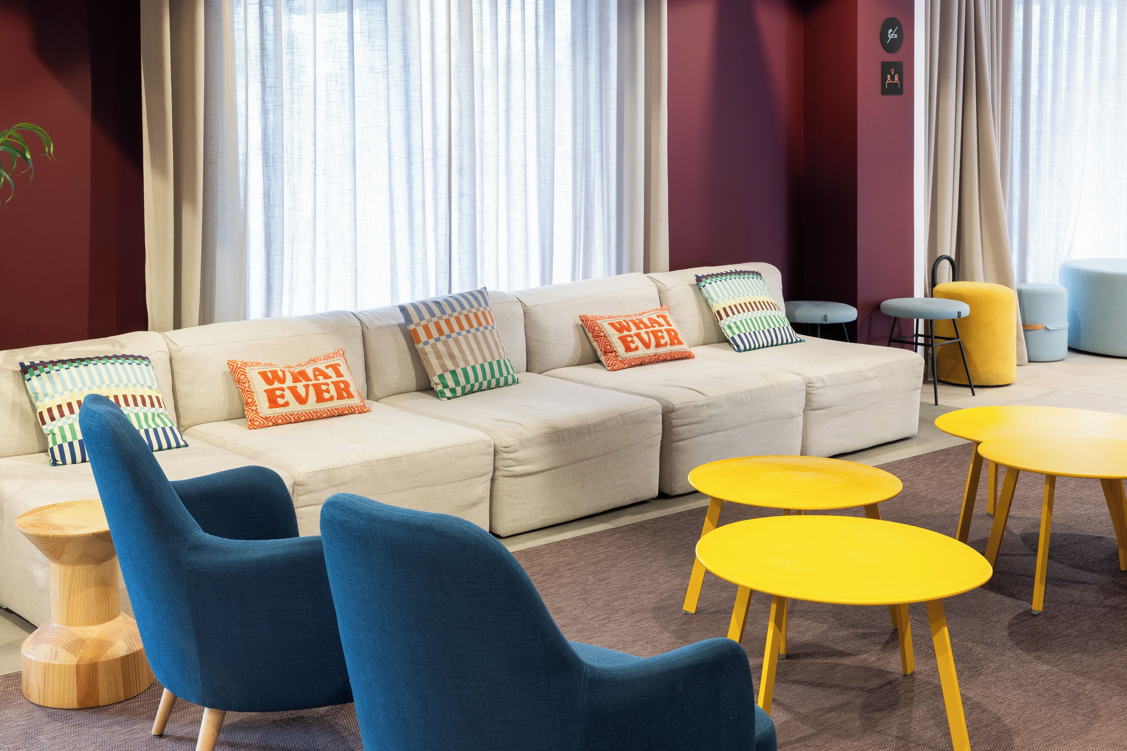 A modern living room with a beige sofa, blue armchairs, and yellow tables.