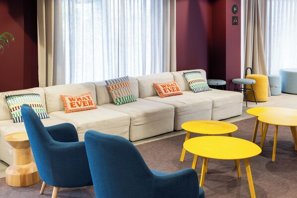 A modern living room with a beige sofa, blue armchairs, and yellow tables.
