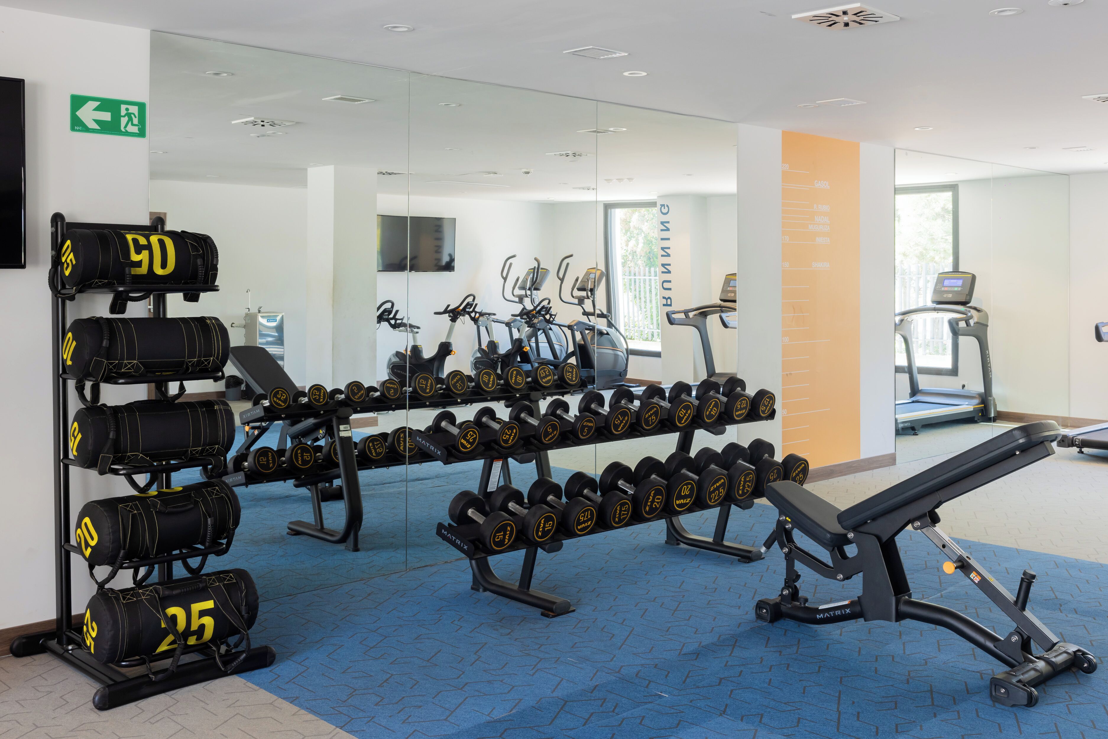 Ein Fitnessraum mit Trainingsgeräten, Kurzhanteln und einer Trainingsbank.