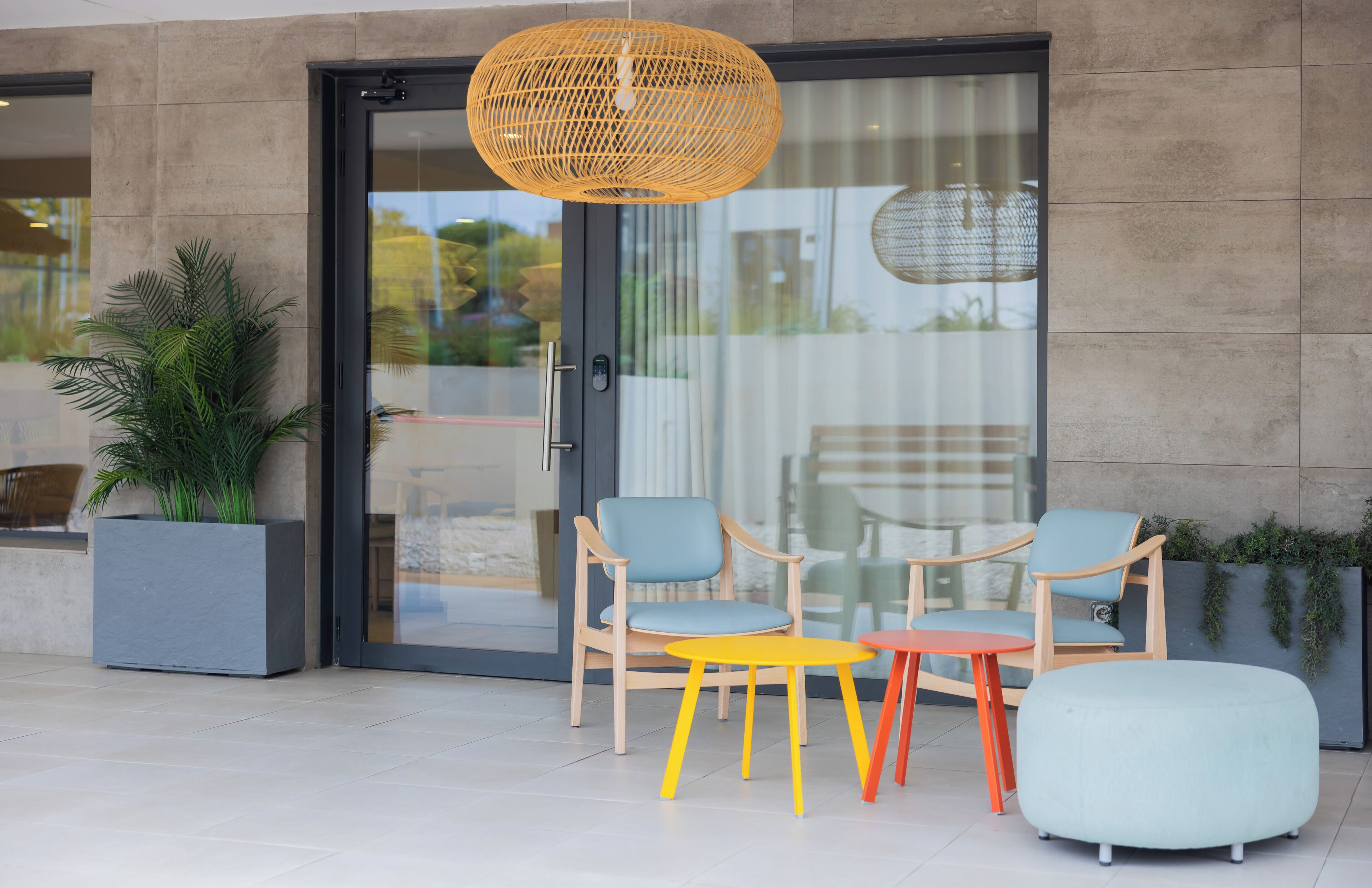 An outdoor seating area with modern chairs and a table, a large woven pendant light, and a potted plant.