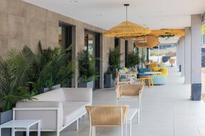 Un espace intérieur moderne avec un canapé blanc, des fauteuils en osier et une table jaune.