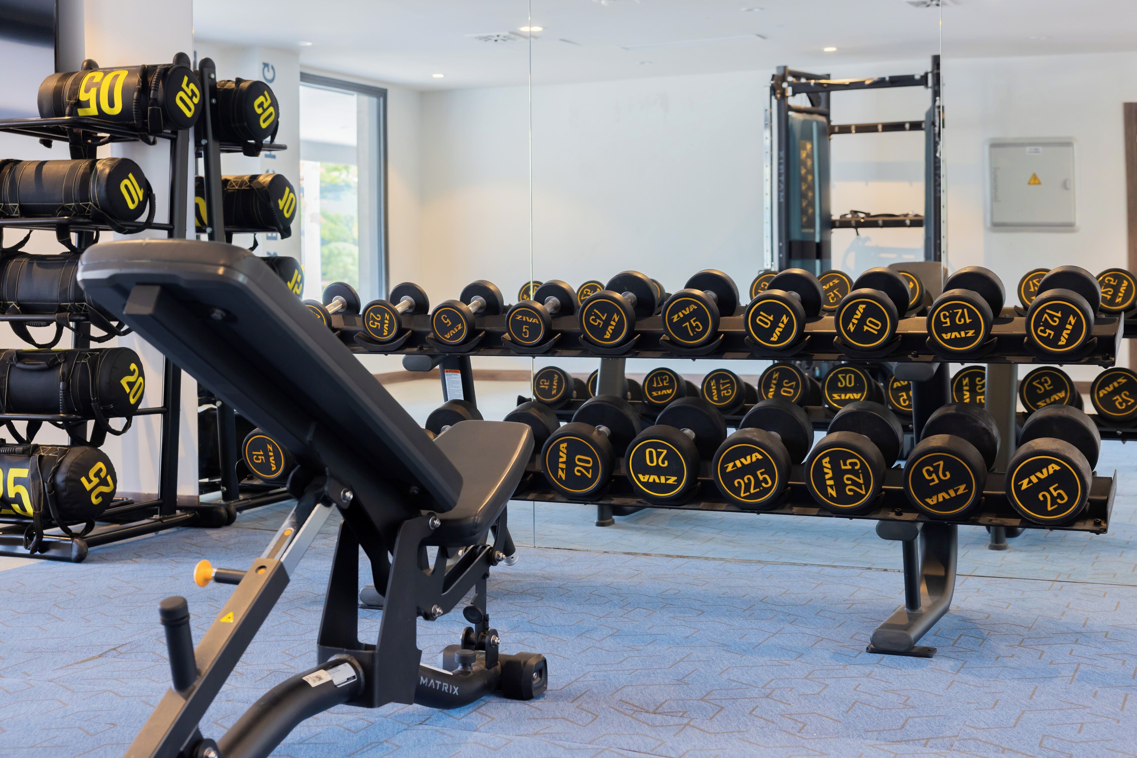 A gym with a bench and a rack of dumbbells.