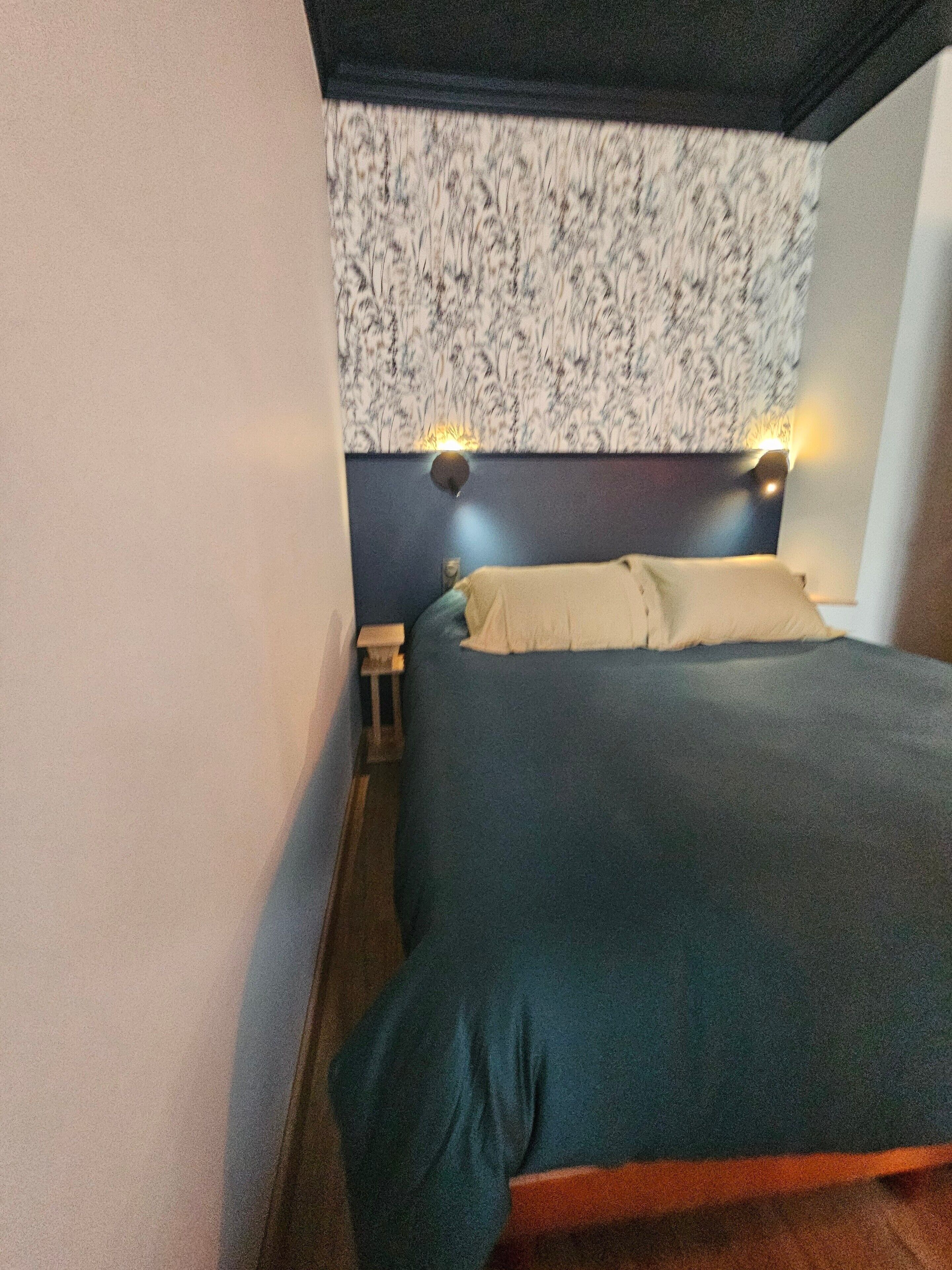 A bedroom with a bed, nightstands, and wall-mounted lights.