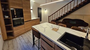 Eine moderne Küche mit Kochinsel, Holzschränken und einem eingebauten Backofen.