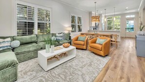 A spacious living area with a green sofa set, a white coffee table, and an orange armchair. - Seafarer Lodge - 2 properties - one roof one price! (Jekyll Island)