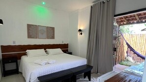 A bedroom with a bed, bedside table, bench, and a view of an outdoor area with a hammock. - La Fluorita Hospedaria (Morro Do Chapeu)