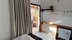 A hotel room with a bed, a desk, a small refrigerator, an air conditioner, and a view of the outside. - La Fluorita Hospedaria (Morro Do Chapeu)