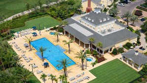 An aerial view of a large property with a central swimming pool surrounded by sun loungers and palm trees, a covered patio area, and a well-maintained lawn. - High End Resort 7Beds Private Pool Gym Near Disney (Kissimmee)