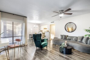 A modern living room with a sofa, armchair, and coffee table. A dining area with a table and chairs is visible in the background. - Prime Location • Walk to AT&T Stadium & Texas Live (Arlington)