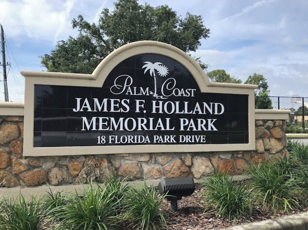 A sign for James F. Holland Memorial Park with a palm tree logo, located at 18 Florida Park Drive.
