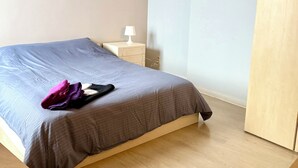 A bedroom with a bed, a nightstand, a lamp, and a wooden wardrobe. - 3 min to the Grand-Place (Brussels)