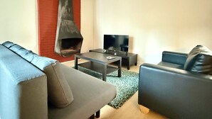 A modern living room with a fireplace, a sofa, a coffee table, and a TV. - 3 min to the Grand-Place (Brussels)