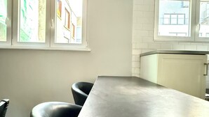 A kitchen with a long countertop, two black bar stools, and windows with views of buildings. - 3 min to the Grand-Place (Brussels)